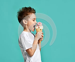 Baby boy kid eat raspberry and vanilla ice cream in waffles cone on blue mint