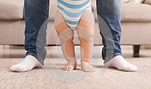 Baby boy learning to walk with help of father