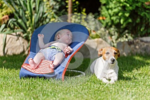 Baby boy lies on a deck-chair on green lawn