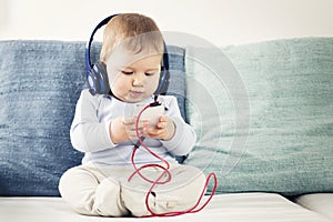 Baby boy listening music at earphones with iphone in hands.