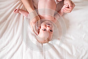 Baby boy lying on bed, held by his mother