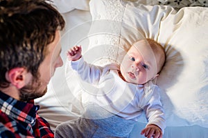 Baby boy lying on bed, with his father