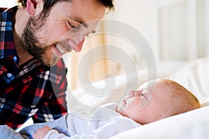 Baby boy lying on bed, with his father