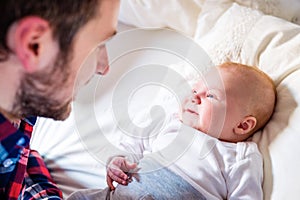 Baby boy lying on bed, with his father