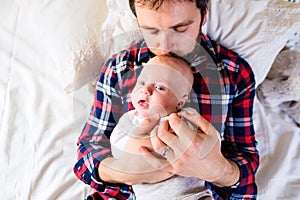 Baby boy lying on bed, next to his father