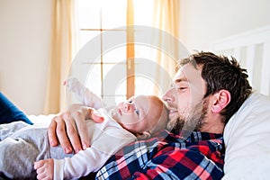 Baby boy lying on bed, next to his father