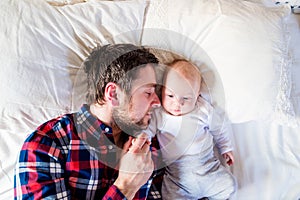 Baby boy lying on bed, next to his father