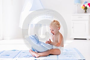 Baby boy with milk bottle in sunny nursery