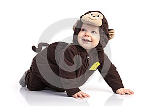 Baby boy in monkey costume looking up over white