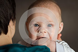 baby boy in mother& x27;s arms looking over her shoulder