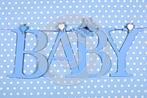 Baby boy nursery blue BABY letters bunting hanging from pegs on a line against a blue polka dot background