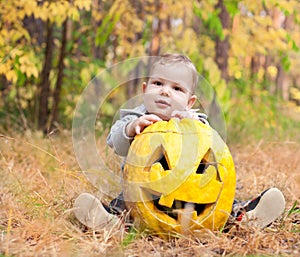 Baby boy outdoors with real pumpkin