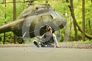 Baby boy in pilot helmet with glasses on asphalt road