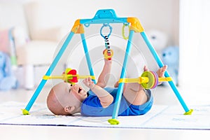 Baby boy on play mat. Child playing in gym.