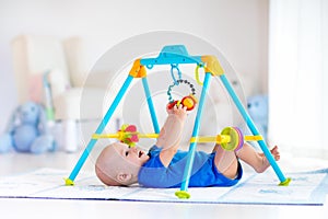 Baby boy on play mat. Child playing in gym.