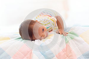 Baby boy playing on bed in sunny nursery