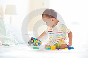 Baby boy playing on bed in sunny nursery