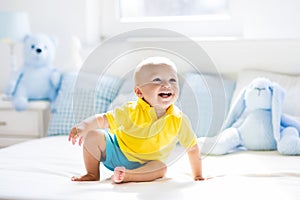 Baby boy playing on bed in sunny nursery