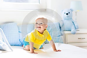 Baby boy playing on bed in sunny nursery