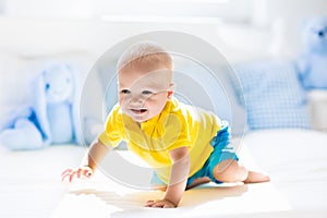 Baby boy playing on bed in sunny nursery