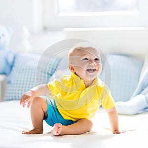 Baby boy playing on bed in sunny nursery