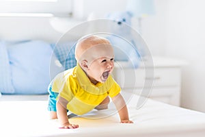 Baby boy playing on bed in sunny nursery