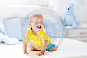 Baby boy playing on bed in sunny nursery