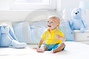 Baby boy playing on bed in sunny nursery