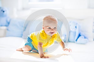 Baby boy playing on bed in sunny nursery