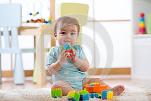 Baby boy playing with colorful plastic bricks on the floor. Toddler having fun and building out of constructor bricks