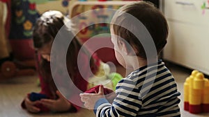 Baby boy playing with his sister in the nursery