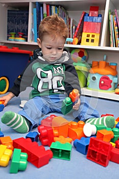 A baby boy playing with plastic blocks