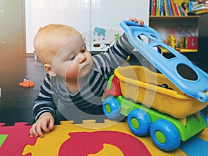 Baby boy playing with toy car on the floor at home