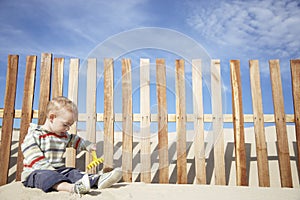 Baby Boy Playing With Toy Rake On Beach