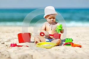 Baby boy playing with toys and sand on beach