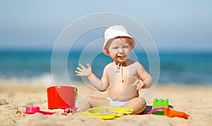 Baby boy playing with toys and sand on beach