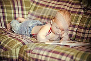 Baby boy read book on sofa