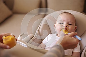 Baby boy refusing to eat porridge while mother trying to feed him