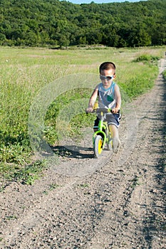 Baby boy riding on his first bike without pedals