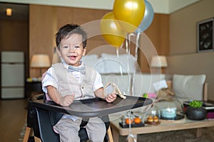 Baby boy\'s first birthday with cake in balloons