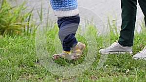 Baby boy's first steps, mother follows, close-up, slow motion