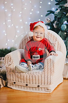 Baby-boy in Santa Claus suit sitting under the Christmas tree
