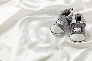 Baby boy shoes on white satin, copy space