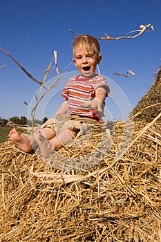 Baby boy sit on a hayrick