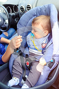Baby boy sitting in child car seat. Mother and child in car. Safety driving concept
