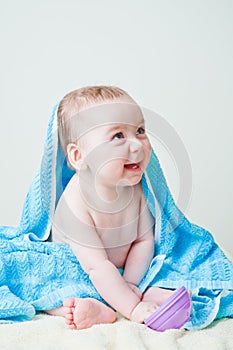 Baby Boy Sitting Covered by Blue Towel Holding Toy