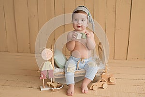 Baby boy sitting on crib. Children Protection Day. Happy childhood. Early child development. Educational wooden toys. Mother`s da
