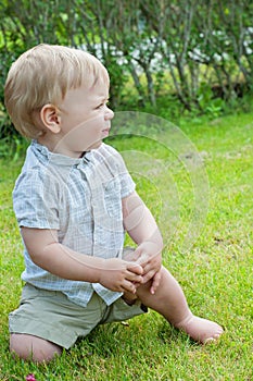 Baby boy sitting on green grass