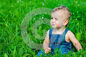 Baby boy sitting on green grass in park