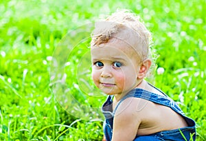 Baby boy sitting on green grass in park